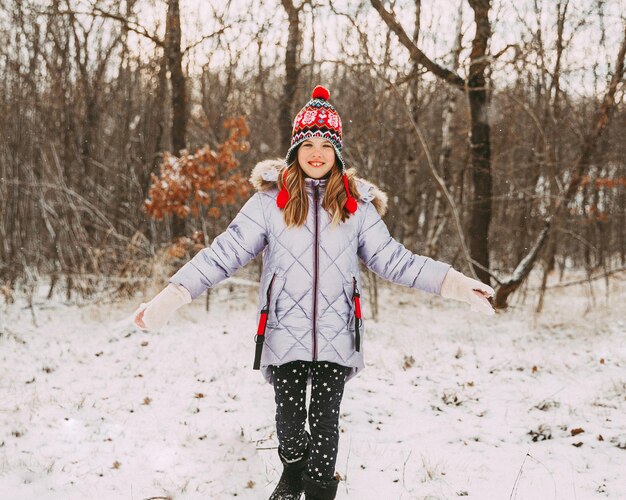 Joyeuse petite fille joyeuse s'amusant dans la forêt un jour d'hiver. l'enfant joue avec la neige.