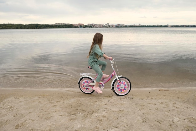 Joyeuse petite fille joyeuse avec son vélo sur la bande de la rivière dans la nature