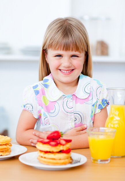 Joyeuse petite fille mangeant des gaufres avec des fraises