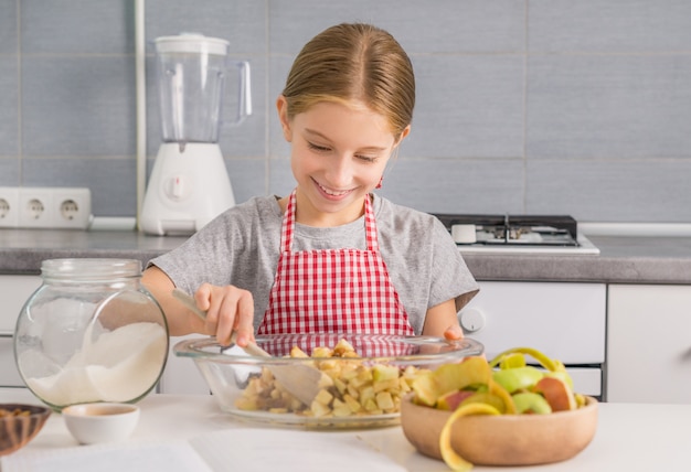 Joyeuse petite fille mélangeant des ingrédients pour le remplissage de strudel