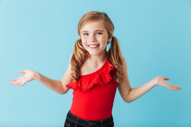 Joyeuse petite fille portant un maillot de bain debout isolée sur un mur bleu, s'amusant