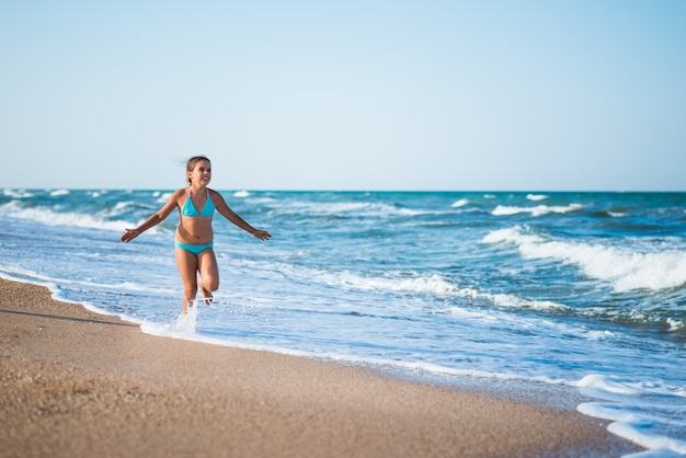 Joyeuse petite fille profite d'une journée à la plage tout en se détendant en mer par une chaude journée d'été ensoleillée. Concept de vacances d'été et de détente