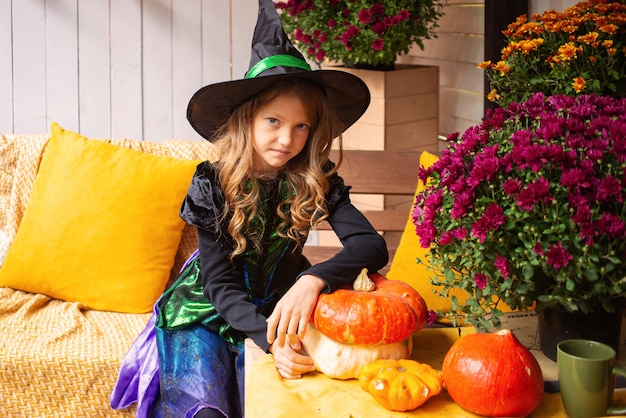 Joyeuse petite fille riante mignonne d'Halloween en costumes de sorcière célèbre l'halloween