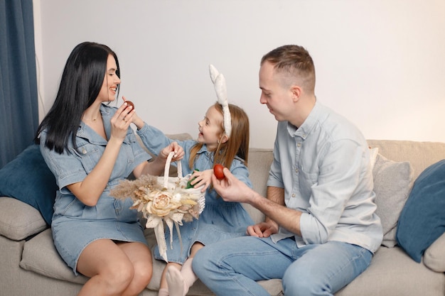 Joyeuse réunion de famille sur un canapé dans le salon se préparant pour les oeufs de Pâques ensemble