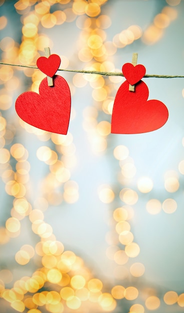 Joyeuse Saint-Valentin avec des coeurs rouges accrocher avec des pinces à linge sur des lumières de corde et bokeh