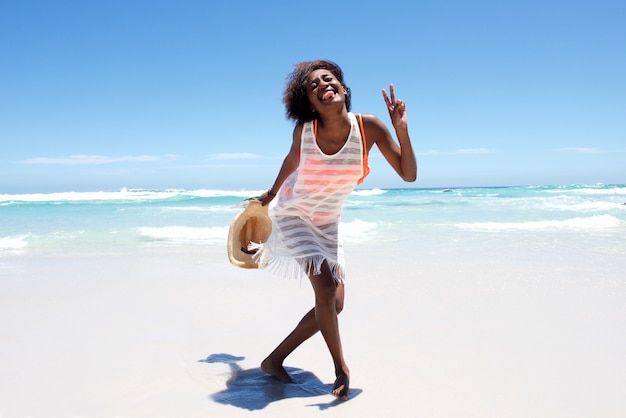 Joyeuse séduisante jeune femme africaine appréciant marcher sur la plage