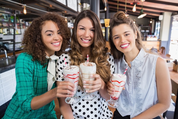 Joyeuses amies posant avec des boissons au restaurant