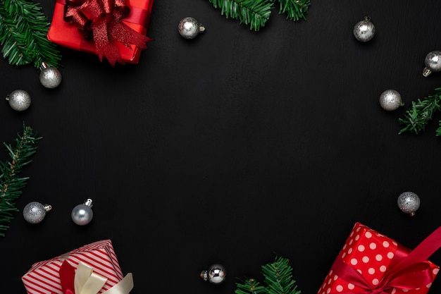 Joyeuses décorations de Noël. Boîte cadeau d'objets de différence essentielle à plat et sapin sur papier noir moderne