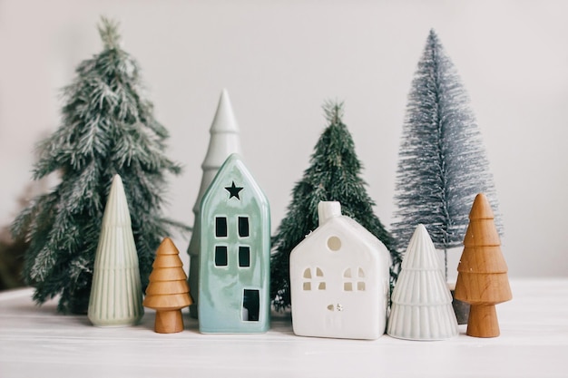 Joyeuses fêtes Maisons miniatures en céramique de village confortable Arbres de Noël en bois et faits à la main Petites maisons et arbres de Noël sur fond blanc Décor moderne et festif