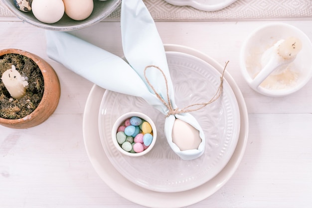 Joyeuses fêtes de pâques au printemps décor de maison festif nourriture traditionnelle œuf de poule beige blanc enveloppé dans un tissu bleu pâle comme des oreilles de lapin ou de lapin dans une assiette et de petits œufs de bonbons sur la table