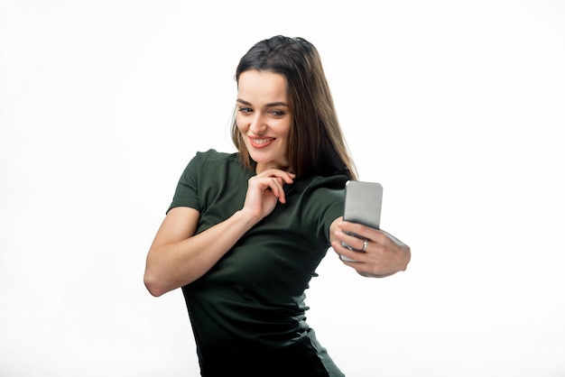 Joyeuses jeunes femmes faisant selfie par son smartphone. Tee-shirt heureux jolie fille aux cheveux noirs tout droit rend selfie avec un sourire fantastique