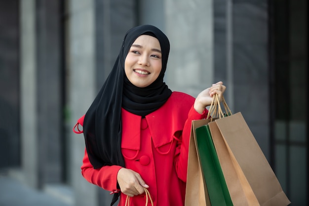 Joyeuses jeunes femmes tenant un sac à provisions à l'extérieur.