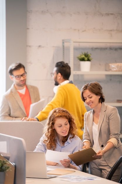 Joyeuses jeunes filles entreprenantes regardant le rapport de vente et discutant d'un nouveau projet au bureau de l'entreprise