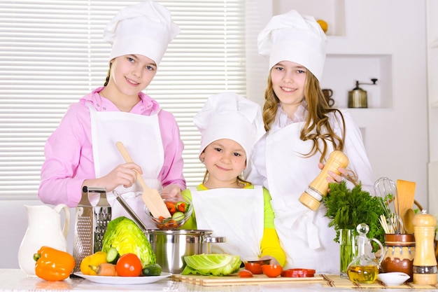 Joyeuses jolies filles cuisinant un plat de légumes