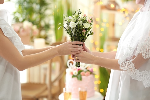 Joyeuses mariées tenant un bouquet de belles fleurs sur un mariage lesbien