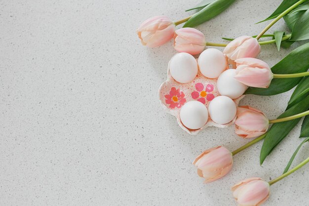 Joyeuses Pâques Belles tulipes et oeufs naturels sur une table moderne Plat de Pâques élégant avec espace de copie Porte-oeufs fait main avec tulipes roses