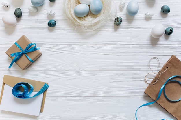 Joyeuses Pâques sur carte de voeux avec boîte actuelle, oeufs bleus et blancs dans le nid