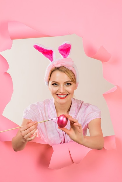 Joyeuses Pâques. Chasse aux oeufs. Femme aux oreilles de lapin peignant des oeufs. Concept de jour de Pâques.