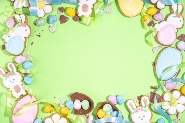 Joyeuses Pâques colorées flatlay Oeufs de Pâques colorés sucrés et au chocolat Biscuits glacés au sucre avec ruban de vacances festif sur fond vert clair vue de dessus espace de copie