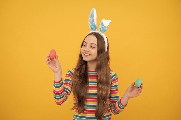 Joyeuses pâques enfant fille dans des oreilles de lapin de lapin montrant des oeufs peints pour les vacances de pâques