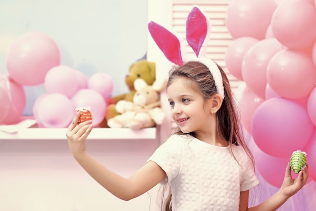 Joyeuses Pâques. Enfant avec des oeufs de Pâques. Mignonne petite fille portant des oreilles de lapin.