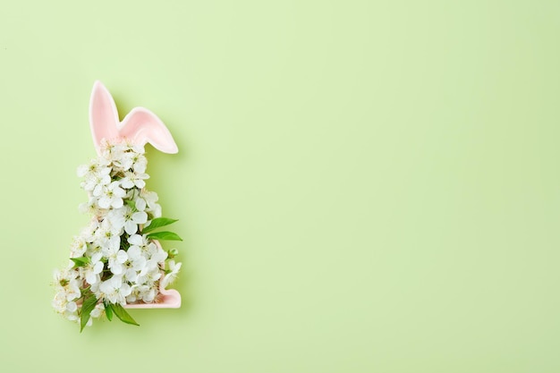 Joyeuses Pâques Forme rose en céramique de lapin de Pâques avec bouquet rond ressorts fleurs de cerisier ou de pommier frais sur fond vert Carte de Pâques de printemps avec espace de copie Concept de Joyeuses Pâques Mock up