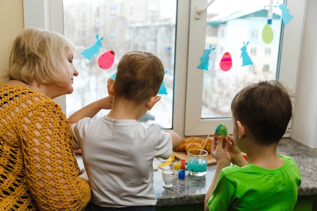 Joyeuses Pâques. Une grand-mère et ses petits-fils peignant des œufs de Pâques. Héhé, préparation pour Pâques à la maison