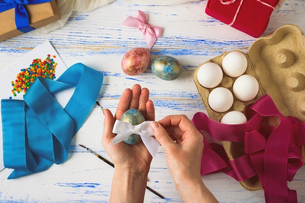 Joyeuses Pâques. Des mains féminines peignent et décorent des oeufs de Pâques sur une table en bois