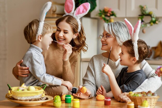 Joyeuses pâques mère de famille grand-mère et enfants peignent des œufs pour les vacances