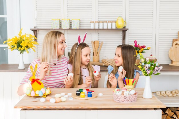 Joyeuses Pâques. La mère et les filles dessinent des œufs de Pâques. Une famille heureuse se prépare pour Pâques.