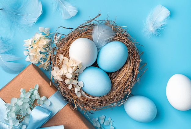 Joyeuses Pâques un nid avec des oeufs de Pâques gros plan sur un fond bleu Vue de dessus