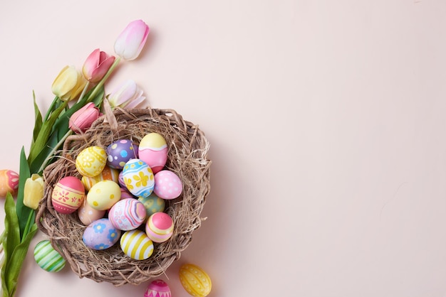 Joyeuses Pâques oeufs colorés dans le nid et la fleur sur fond de papier avec espace de copie