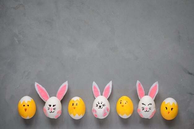 Joyeuses Pâques oeufs de fond décorés comme des lapins et des poussins sur l'espace de copie de fond texturé gris