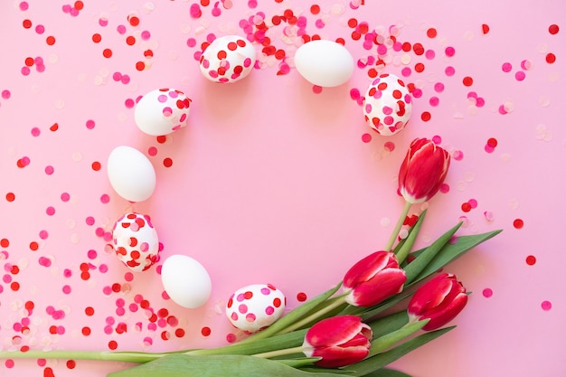 Joyeuses Pâques. Oeufs de Pâques décorés de confettis en papier et de tulipes