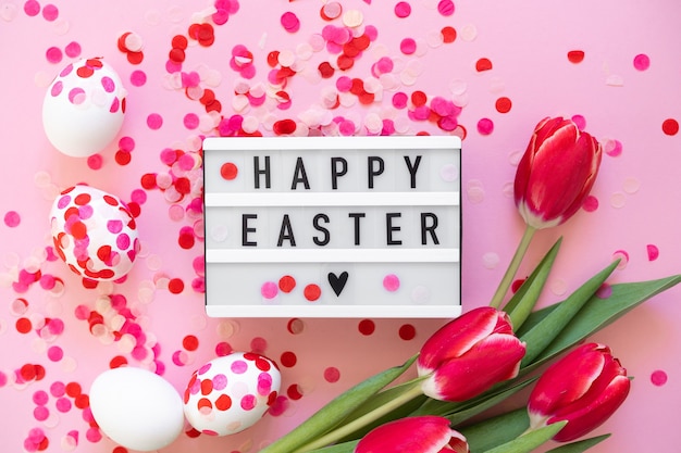 Joyeuses Pâques. Oeufs de Pâques décorés de confettis en papier et de tulipes