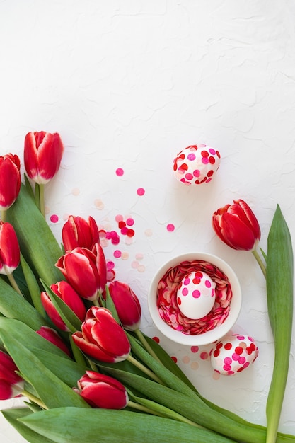 Joyeuses Pâques. Oeufs de Pâques décorés de confettis en papier et de tulipes