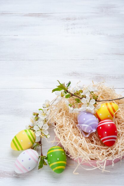 Joyeuses Pâques peint des oeufs avec des fleurs sur une table colorée en bois, fond de vacances pour votre carte. Chasse aux œufs, espace copie