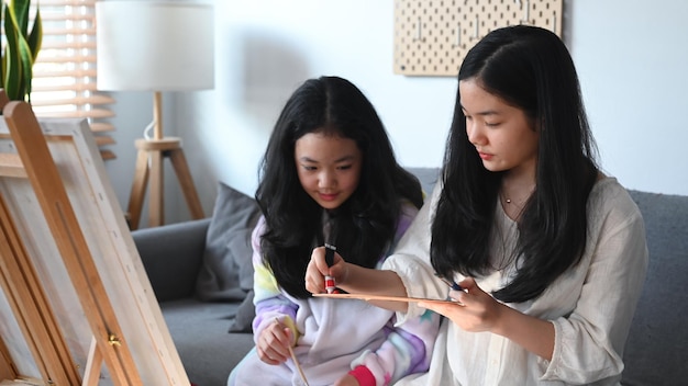 Joyeuses petites filles peignant une photo à la maison le week-end