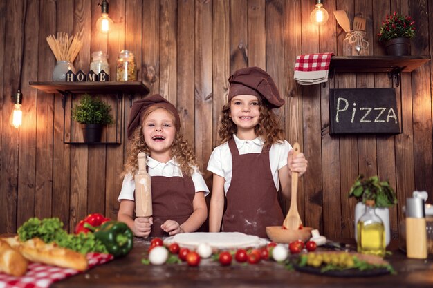 Joyeuses soeurs cuisant une pizza ensemble