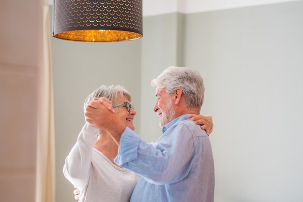 Photo joyeux actif vieux couple romantique à la retraite dansant en riant dans le salon femme d'âge moyen heureuse et mari âgé s'amusant à la maison souriants grands-parents âgés se détendant se liant ensemble xa