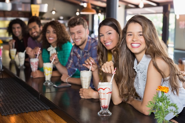 Joyeux amis ayant un smoothie au restaurant