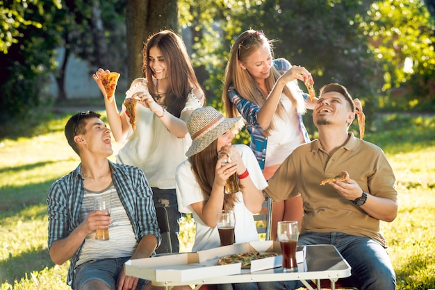 Joyeux amis en pique-nique dans le parc. Manger de la pizza