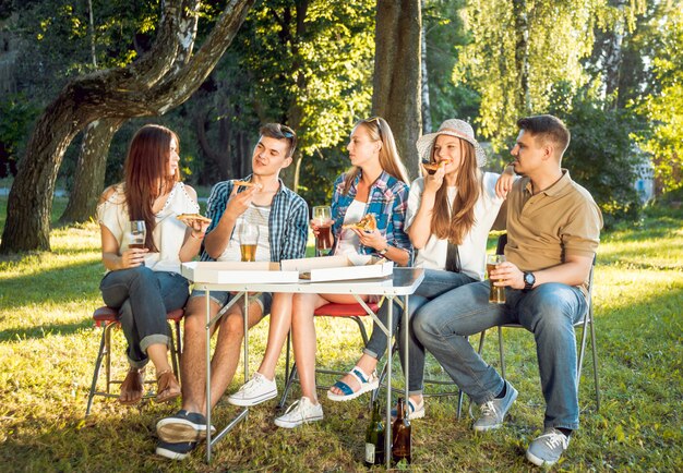 Joyeux amis en pique-nique dans le parc. Manger de la pizza