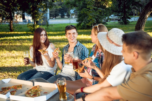 Joyeux amis en pique-nique dans le parc. Manger de la pizza