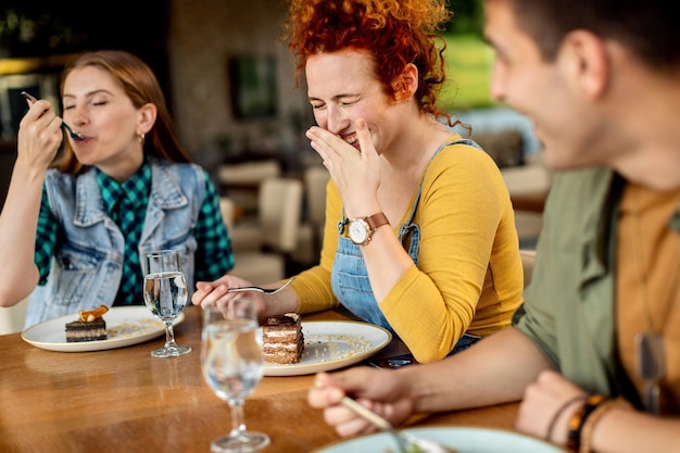 Joyeux amis s'amusant en mangeant un dessert dans un café