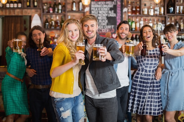 Joyeux amis tenant des verres à bière dans un pub