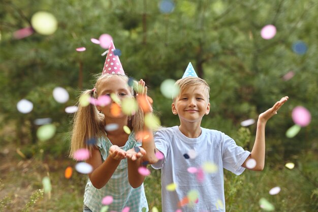 Joyeux anniversaire aux enfants avec des confettis lors d'une fête d'anniversaire en plein air