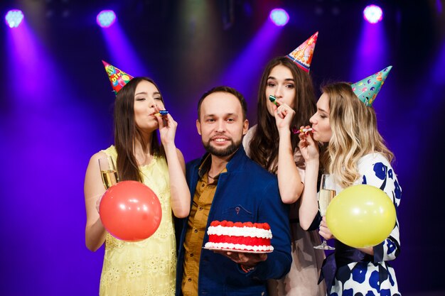 Joyeux anniversaire! Groupe d'amis souriants réunis avec un gâteau.