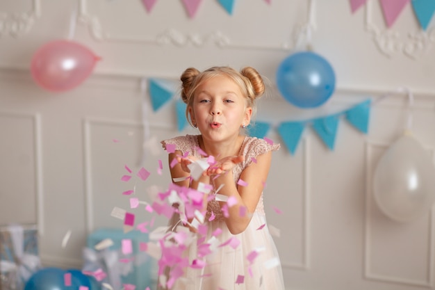 Joyeux anniversaire Portrait d'une jolie blonde mignonne de 7 à 8 ans dans un décor festif avec des confettis et des cadeaux.