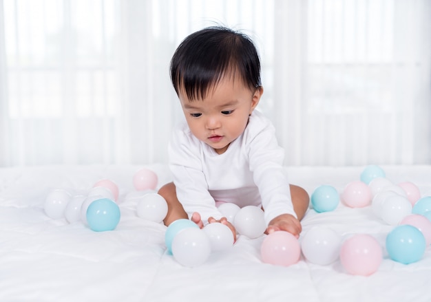 Joyeux bébé jouant à la balle de couleur sur le lit
